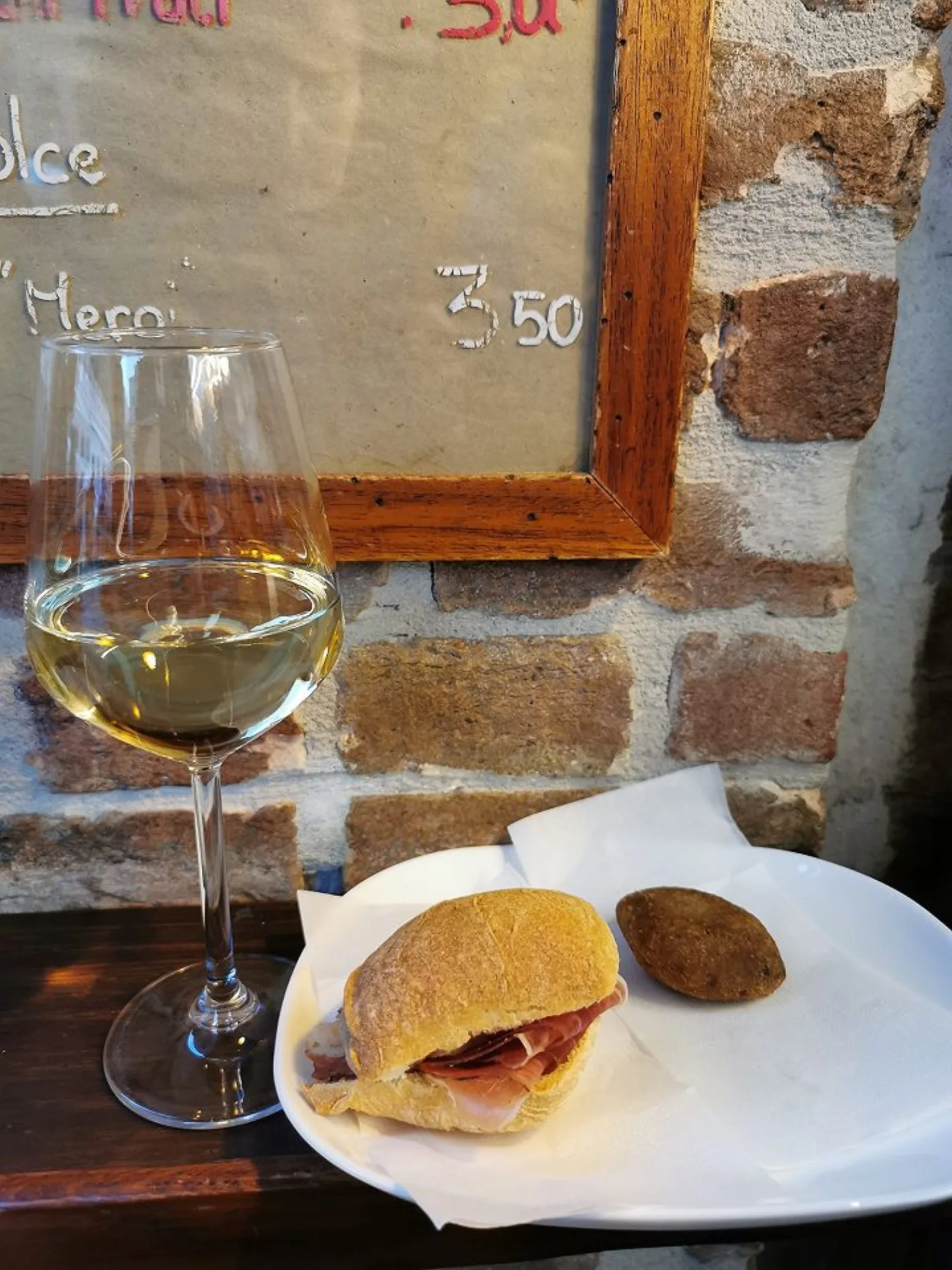 A glass of wine and a cicchetto resting on the Al Mercà counter at Rialto